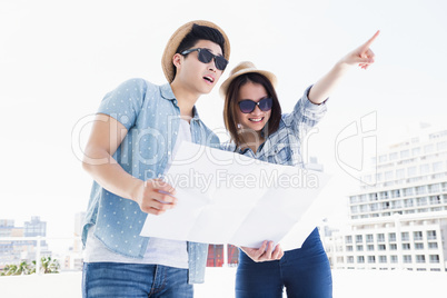 Happy young couple using map for direction