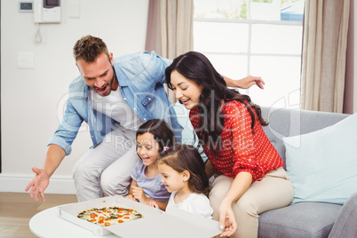 Family of four looking at pizza on table
