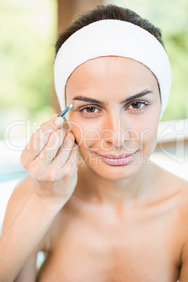Close-up portrait of woman having eyebrows plucked