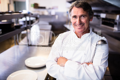 Smiling chef holding ladle in the kitchen