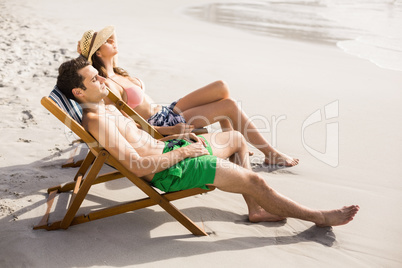 Young couple relaxing on armchair on the beach