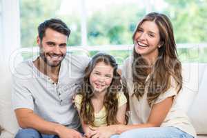 Happy couple sitting with daughter on sofa