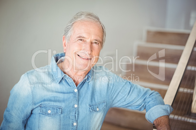 Portrait of smiling senior man against staircase