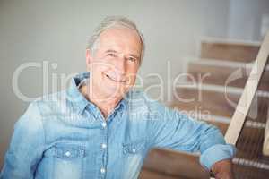 Portrait of smiling senior man against staircase