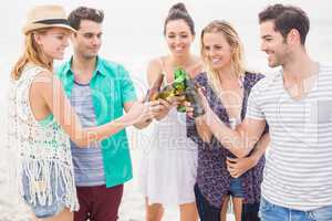 Group of friends toasting beer bottles on the beach