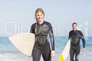 Portrait of couple with surfboard walking on the beach