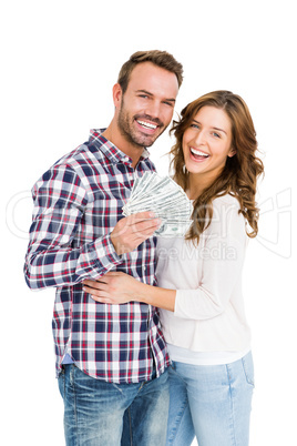 Happy young couple holding fanned out currency note