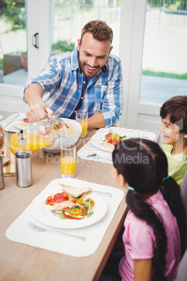 Father pouring juice in glass with children