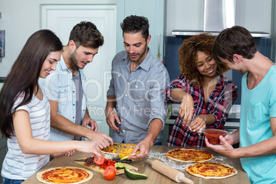 Friends preparing pizza on kitchen table
