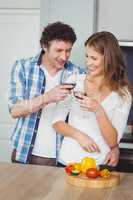 Young couple toasting wine in kitchen