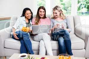 Female friends smiling while looking in laptop