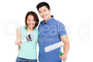 Young couple holding paint brush and paint roller