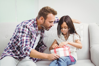 Father helping girl in tying gift box