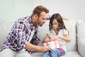 Father helping girl in tying gift box