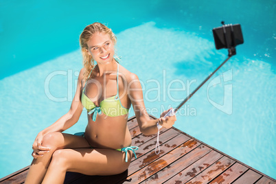 Beautiful woman in bikini taking a selfie by pool side