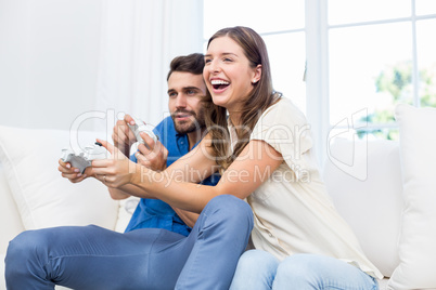 Couple playing video game while sitting on sofa