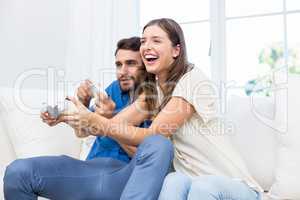 Couple playing video game while sitting on sofa