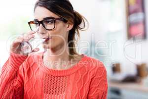 Beautiful young woman drinking water in glass
