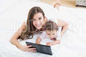 Mother holding tablet PC with baby at home