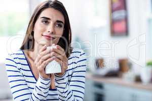 Thoughtful young woman holding mug at home