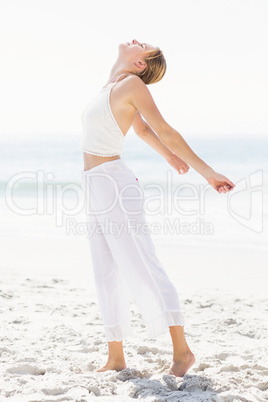 Beautiful woman stretching her arms on the beach