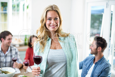 Smiling woman holding red wine glass with friends