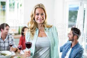 Smiling woman holding red wine glass with friends