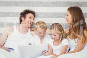 Family with laptop on bed