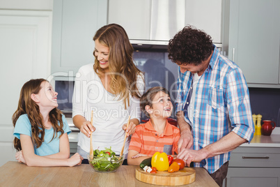 Smiling family preparing vegetable salad