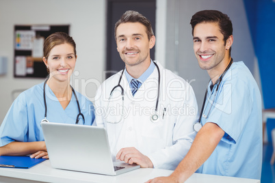 Portrait of smiling doctor and colleagues with laptop