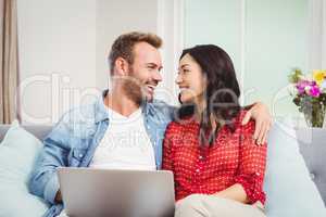 Couple with laptop siting on sofa at home