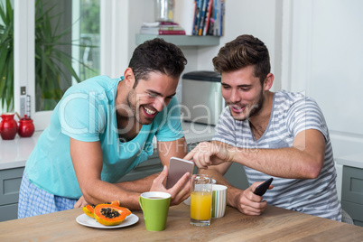 Happy male friends using phone