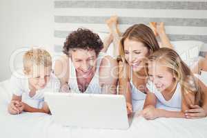 Happy family using laptop on bed