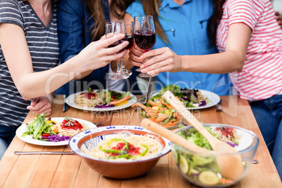 Midsection of friends toasting red wine glasses