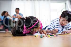 Portrait of brother and sister lying on floor and drawing