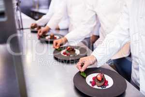 Team of chefs finishing dessert plates in the kitchen