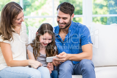 Family looking at smart phone while sitting on sofa