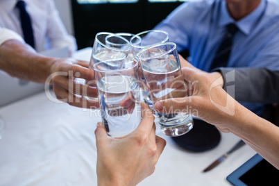 Group of businesspeople toasting glass of water in restaurant