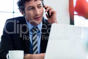 Businessman talking on phone and using his laptop