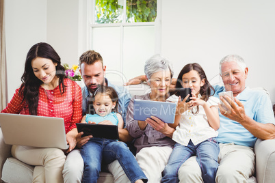 Family using technologies while sitting in sofa