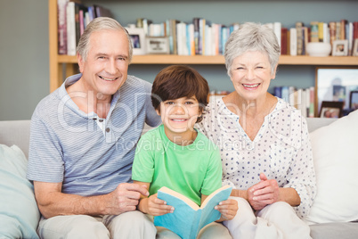 Portrait of grandparents with grandson while holding book