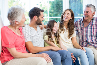 Multi-generation family smiling while sitting on sofa