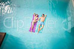 Happy couple relaxing on inflatable raft at swimming pool