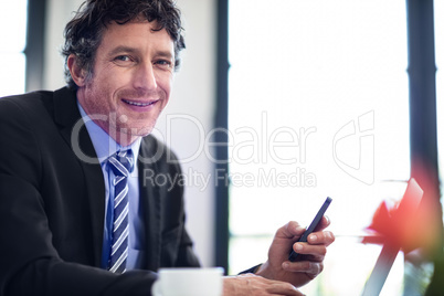 Businessman using phone while working on laptop