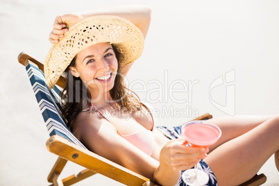 Young woman sitting on armchair with cocktail drink