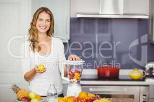 Portrait of smiling woman preparing fruit juice