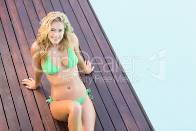 Portrait of beautiful woman in green bikini relaxing by pool sid