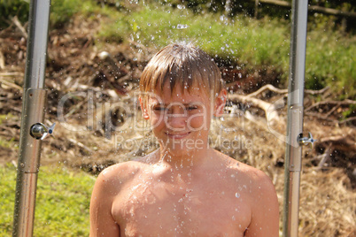 Portrait of Smiling Boy Taking Shower on Beach