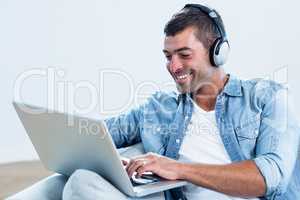 Young man listening to music while using laptop