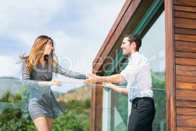 Happy young couple dancing at balcony in resort